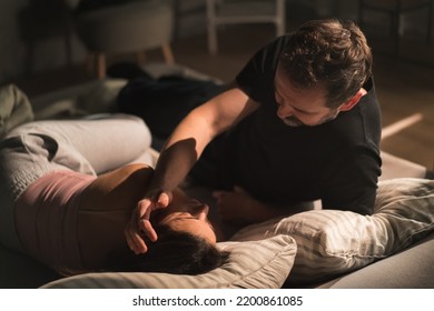 Close-up Of Mid-adult Couple Lying In Bed At Night And Hugging And Looking At Each Other.