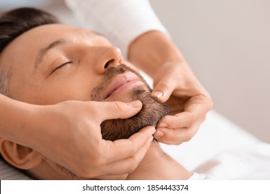Closeup of middle aged man getting healing face massage at luxury spa. Spa therapist making relaxing massage for handsome man, rubbing his bearded chin, copy space. Male cosmetology concept