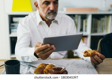 closeup middle aged man using tablet while having breakfast at home