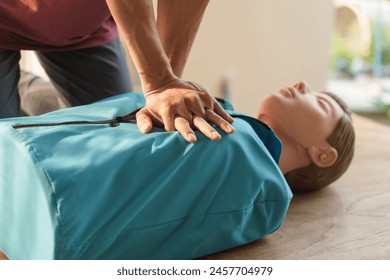 Close-up of middle-aged Asian male hands performing cardiopulmonary resuscitation (CPR) on a training dummy. Vital techniques include defibrillation, chest compressions, and maintaining the airway. - Powered by Shutterstock