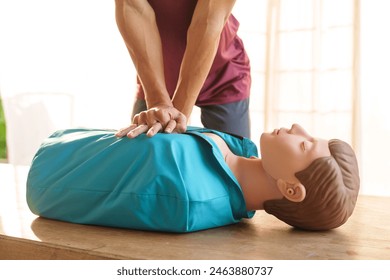 Close-up of middle-aged Asian male hands performing cardiopulmonary resuscitation (CPR) on a training dummy. Vital techniques include defibrillation, chest compressions, and maintaining the airway. - Powered by Shutterstock