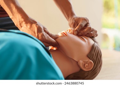 Close-up of middle-aged Asian male hands performing cardiopulmonary resuscitation (CPR) on a training dummy. Vital techniques include defibrillation, chest compressions, and maintaining the airway. - Powered by Shutterstock