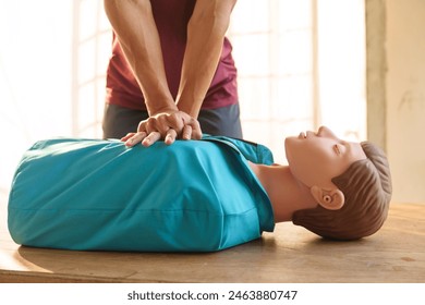 Close-up of middle-aged Asian male hands performing cardiopulmonary resuscitation (CPR) on a training dummy. Vital techniques include defibrillation, chest compressions, and maintaining the airway. - Powered by Shutterstock