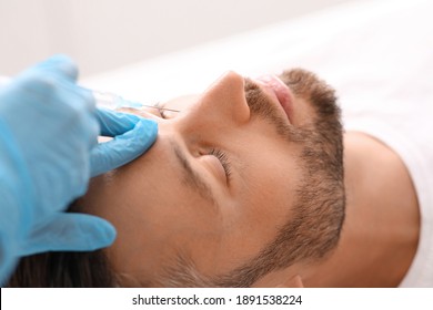 Closeup of middle-aged man getting beauty injection in nose at aesthetic clinic. Plastic surgeon injecting anti-aging filler in handsome bearded man face. Male cosmetology, aesthetic medicine concept