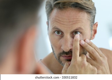 Closeup of middle-aged man insterting contact lens