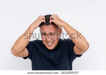 A close-up of a middle-aged man showing annoyance as he vigorously scratches his head, having itchy dandruff issues.