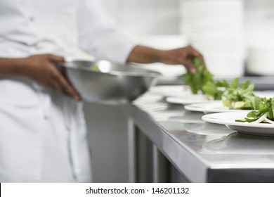 Closeup midsection of a chef preparing salad in the kitchen - Powered by Shutterstock