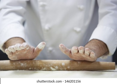 Closeup midsection of a chef rolling dough with rollingpin