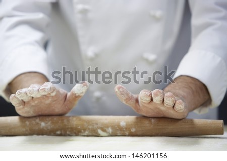 Closeup midsection of a chef rolling dough with rollingpin