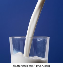 lait en gros plan versé dans un verre et isolé sur fond bleu
