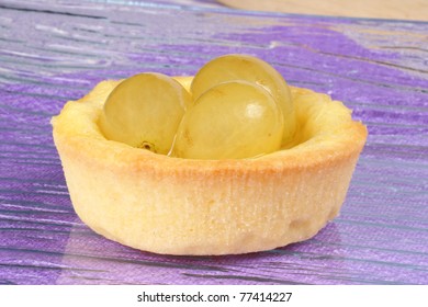 Closeup Of A Mini Grapes Fruit Tart On A Glass Plate Over A Pink Background. With Copy-space. Selective Focus.