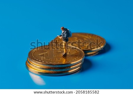 closeup of a miniature adventurer man observing a map standing on a pile of bitcoins on a blue background, depicting the adventurous and risky nature of investing in this virtual currency