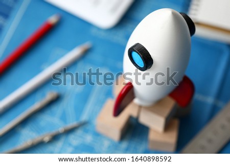 Close-up of miniature rocket standing on table. Macro shot of rocketship as symbol for business project and start-up. Selective focus. Success and growth concept