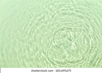 Closeup of mint green transparent clear calm water surface texture with splashes and bubbles. Trendy abstract summer nature background. Mint colored waves in sunlight. 