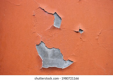 Close-up. A  missing patch of stucco  and paint on the wall exposing the cement brown coat, rest is cracked and peeling. Badly fixed building facade wall covered with cracks in stucco and paint. 