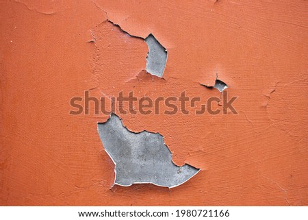 Close-up. A  missing patch of stucco  and paint on the wall exposing the cement brown coat, rest is cracked and peeling. Badly fixed building facade wall covered with cracks in stucco and paint. 