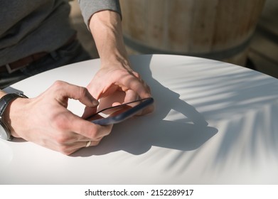 Close-up Of Mobile Phone In Hands On White Table. Sunlight.