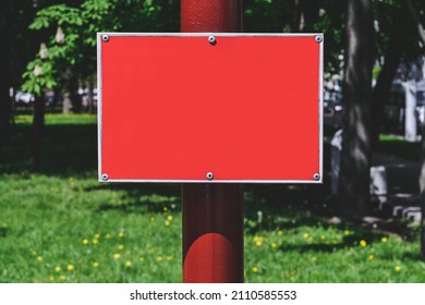 Close-up, Mockup Of A Red Sign On A Pole. Against The Background Of The Park