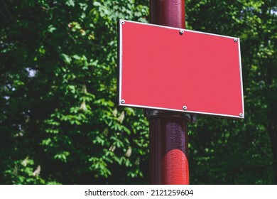 Close-up, Mockup Of A Red Sign On A Pole. Against The Background Of The Park