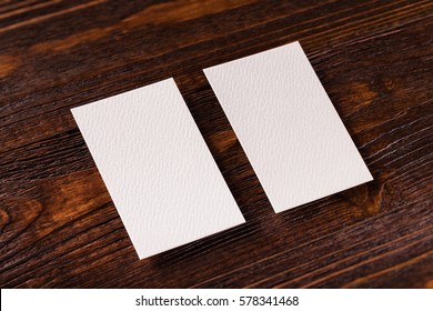 Closeup Mockup Of Two Blank Vertical Business Cards At Brown Wooden Table Background.