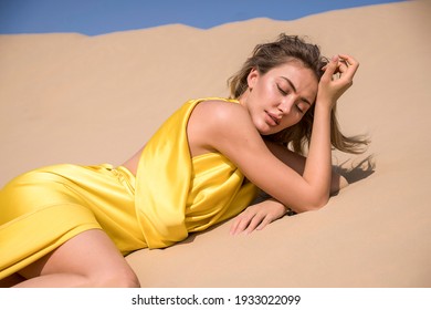 Close-up model face portrait of young Beautiful sexy blonde  woman tanned skin face cosmetic makeup wear silver  accessories, walking in the sand of desert dunes. Hot country, travel.Dress in gold