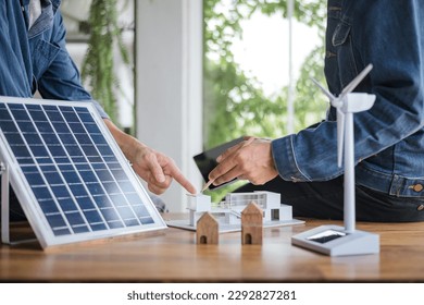 Close-up at model house, Engineers pointing at model house with their hands. To jointly design the use of renewable energy with wind and solar energy. Concept of using renewable energy.
