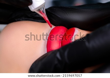 close-up of the models' lips, how the procedure of permanent lip makeup with the help of a tattoo machine takes place