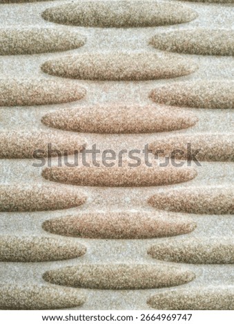 Close-up of a modern abstract surface pattern with a raised texture. The horizontal ellipses, neatly arranged in a staggered format, create a 3D illusion