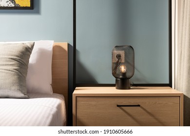 Closeup Of Modern Black Metal Edison Bulb Lamp On Wooden Bedroom Night Table In Contemporary Style Gray Room Interior With Pine Wood Bed And White Cotton Bedlinen