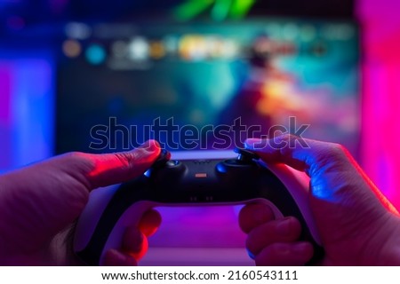Close-up. Modern gamepad. A gamer plays video games on a technological background on a TV screen. Virtual reality, entertainment, communications, cyberspace.