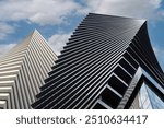 Close-up of a modern glass office building. Reflection of the sky with clouds in the glass of the building. Building exterior, business, construction industry.