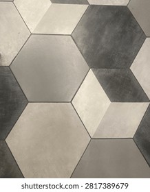 Close-up of modern gray and white hexagonal floor tiles arranged in an abstract geometric pattern, creating a three-dimensional cube optical illusion. Suitable for backgrounds, textures, interior design, and architectural concepts.