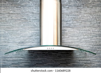 Closeup of modern kitchen exhaust fan above electric, gas, stove, contemporary stone, tiles, tiled wall finish, backsplash