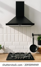 Closeup of modern kitchen interior in white and black tones with frying pan, stove and extractor closeup. Cozy place for cooking concept. Modern household appliances 