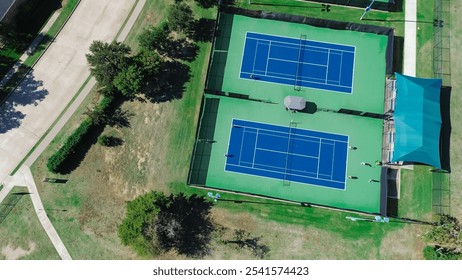 Close-up modern lighted tennis court in sport complex outside Dallas Texas, well-lit hard courts with player practicing group lesson, shaded spectator areas and comfortable benches, ball machine. USA - Powered by Shutterstock