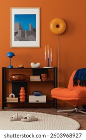 Close-up of modern orange lounge chair and bookshelf against a bold terracotta wall in a cozy home setting.
