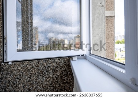 Close-Up of Modern Plastic Window with Pebble Wall and Textured Interior Surface in Daylight. Silicone window open retainer on window sill.