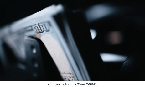 Close-up of a money counting machine sorting hundred dollar bills for currency exchange or cash deposit. Automatic banknote counter in action. Concept of finance, banking and investment. 