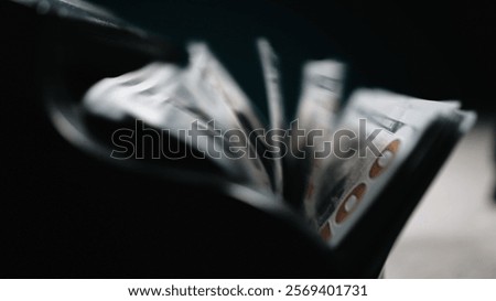 Close-up of a money counting machine sorting hundred dollar bills against a dark background symbolizing wealth, capitalism and investment. Emphasis on currency and economic growth. 