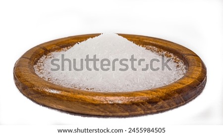 Close-up of monosodium glutamate, MSG in a flat wooden container. It's for seasoning food. White background. Isolated.