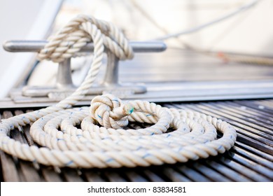 Close-up of a mooring rope with a knotted end tied around a cleat on a wooden pier/ Nautical mooring rope - Powered by Shutterstock