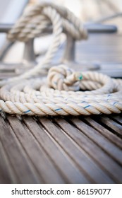 Close-up of a mooring rope with a knotted end tied around a cleat on a wooden pier/ Mooring rope
