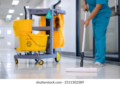 A close-up of a mop cleaning the office floor with a cleaning cart, mop cleaning tools, and equipment made of epoxy flooring - Powered by Shutterstock