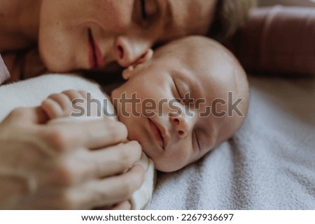 Close-up of mother cuddling with her newborn baby in their bad.