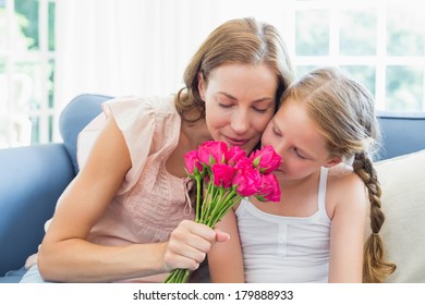 Close-up Of Mother And Daughter Smelling Flowers In The Living Room At Home