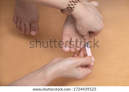 Closeup of mother hand cutting nails for her son at home by using nail clipper