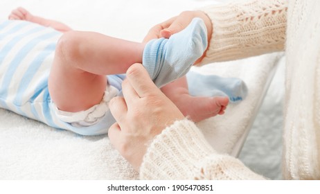 Closeup of mother putting on socks on her little baby son lying on changing table. Concept of babies and newborn hygiene and healthcare. Caring parents with little children