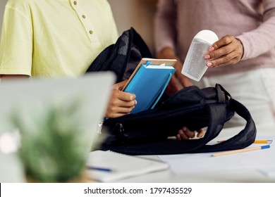 Close-up Of Mother And Son Packing For School And Adding Hand Sanitizer In Backpack. 