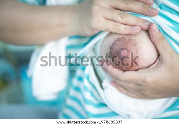 Close-up of a mother\
squeezing milk out of her breast by hand. Hand expression or manual\
expression