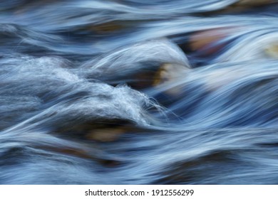 Closeup of Motion-Blurred Water Rapids Flowing over a Cobble Sto - Shutterstock ID 1912556299
